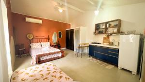 a bedroom with a bed and a kitchen with a refrigerator at Casa das Lunas in Praia do Forte