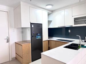 a kitchen with a black refrigerator and white cabinets at Sarah Homestay - Masteri Thao Dien in Ho Chi Minh City