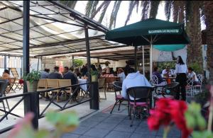 a group of people sitting at tables under a green umbrella at Hotel Palmas Teotihuacán in San Juan Teotihuacán