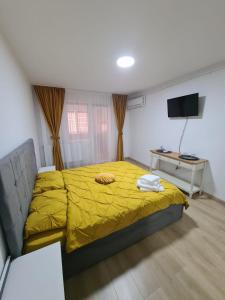ピテシュティにあるGarsoniera Luxury Kevinのベッドルーム1室(黄色い毛布付きのベッド1台付)
