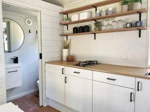 a kitchen with white cabinets and a mirror at Mornington Peninsula Tiny House - Tiny Stays in Red Hill