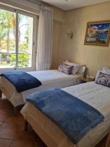 two beds in a hotel room with a window at Appartement Bouznika Bay Golf in Bouznika