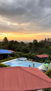 una piscina con techo rojo y puesta de sol en Finca Hotel Villa Celeste, en Quimbaya