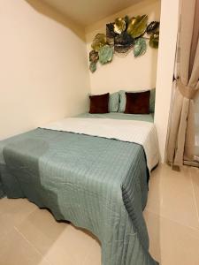 a bedroom with a bed with a green blanket at Lengs Place 2 - Studio Unit with Balcony at Inspiria Condo in Davao City