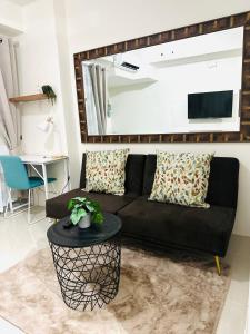 a living room with a black couch and a table at Lengs Place 2 - Studio Unit with Balcony at Inspiria Condo in Davao City