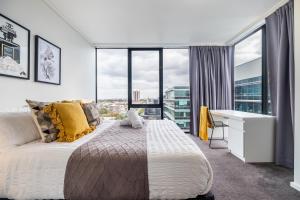 Un dormitorio con cama, escritorio y ventanas en Mega Style Apartments Capri, en Melbourne