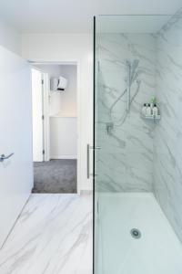 a white bathroom with a shower with a glass door at 3 Bedroom Hagley Park Paradise in Christchurch