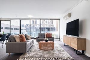 Una sala de estar con un sofá y un televisor de pantalla plana. en Mega Style Apartments Capri, en Melbourne