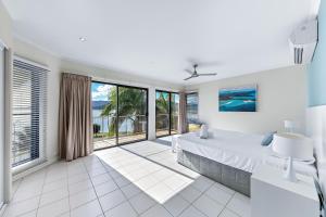 エアリービーチにあるWhitsunday Beachfront Apartment on Broadwaterの白いベッドルーム(大きなベッド1台、大きな窓付) +16枚の写真