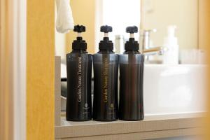 three black bottles sitting on a shelf next to a sink at HOTEL Third Place Hakata in Fukuoka