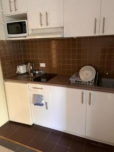 a kitchen with white cabinets and a microwave at H & D Apartments in Melbourne