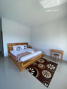 a bedroom with a wooden bed and a rug at Batur Pyramid Guesthouse in Kintamani