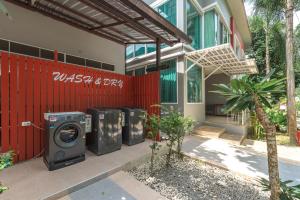 uma casa com três máquinas de lavar roupa ao lado de uma cerca vermelha em The One Cozy Vacation Residence SHA Hotel em Chalong
