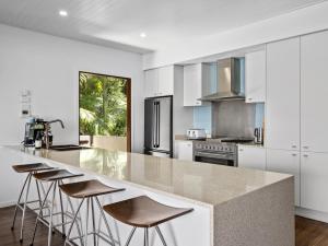 a kitchen with white cabinets and a large island with bar stools at Liapari Beach House in Sapphire Beach