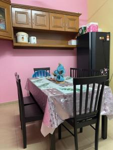 a dining room table with a pink wall and a black refrigerator at EQ Malay Modest Homestay Port Dickson in Port Dickson