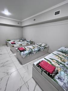 a row of four beds in a room at Hostel_inJoy in Shymkent