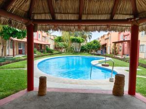 a large swimming pool with a thatched roof at Casa Morrocoy Ixtapa in Ixtapa