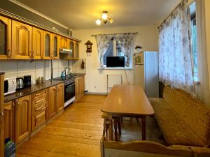 una cucina con armadi in legno, tavolo e divano di Villa M a Mykulychyn