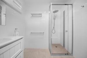 a glass shower in a bathroom with a sink at CocoBrew Boutique Apartments in Rockhampton