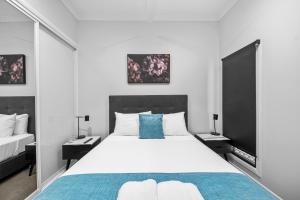 a bedroom with a large white bed with blue pillows at CocoBrew Boutique Apartments in Rockhampton
