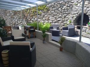 un patio con sillas y una pared de piedra. en Apartement Noggler, en Malles Venosta