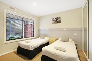 two beds in a room with a window at Grevillea Gardens Unit 8 in Bright