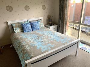 a bedroom with a bed with blue pillows and a window at KG Ensuite in Palmerston North