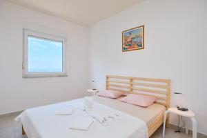 ein weißes Schlafzimmer mit 2 Betten und einem Fenster in der Unterkunft Apartmets Sutmiholjska in Babino Polje