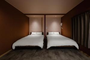 two beds sitting next to each other in a room at The Landmark in Furano