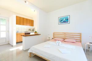 ein weißes Schlafzimmer mit einem Bett und einer Küche in der Unterkunft Apartmets Sutmiholjska in Babino Polje