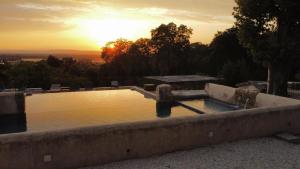 un bassin d'eau avec le coucher du soleil en arrière-plan dans l'établissement Mas provençal dans un lieu exceptionnel, à Bollène