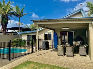a covered patio with a table and chairs and a surfboard at Surf Club House, Pet Friendly, Sunshine Coast, Holiday House, Marcoola in Marcoola