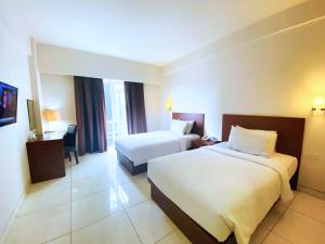 a hotel room with two beds and a desk at The Tusita Hotel in Kuta