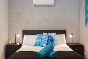 a bed with blue pillows on it with two lamps at Binks Beach House - South Fremantle in South Fremantle