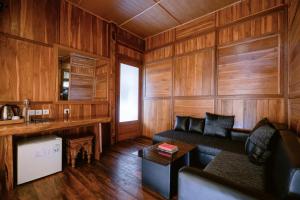a living room with wooden walls and a couch at Munduk Menir Villas in Munduk