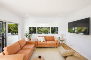 a living room with a couch and a tv at Aura Apartment-LJHooker Yamba in Yamba