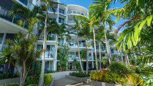 an apartment building with palm trees in front of it at Vision Apartments in Cairns