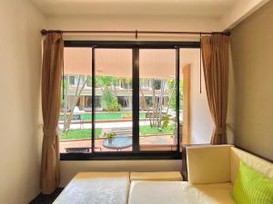 a bedroom with a window with a view of a yard at Hotel La Villa Khon Kaen in Khon Kaen