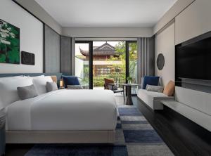 1 dormitorio con 1 cama blanca y TV en Kimpton Bamboo Grove Suzhou, an IHG Hotel, en Suzhou