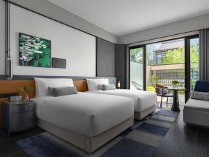 1 dormitorio con 2 camas y balcón en Kimpton Bamboo Grove Suzhou, an IHG Hotel, en Suzhou