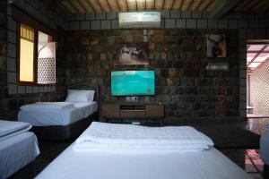 a bedroom with two beds and a flat screen tv at nbz chalet Jasmine stairs in Al ‘Aqar