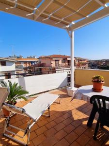 een patio met een tafel en stoelen op een dak bij Attico con terrazzo Relax in Ladispoli