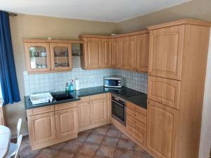 a kitchen with wooden cabinets and black counter tops at Rügen Schaprode Bungalow - barrierefrei - kleine Hunde auf Anfrage willkommen in Schaprode +8 photos