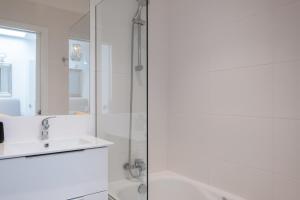 een witte badkamer met een wastafel en een douche bij GuestReady - Anakaj House in Funchal