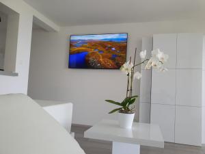 een witte kamer met een vaas met bloemen op een tafel bij Jacuzzi Studio Apartment in Matulji