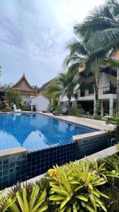 a large swimming pool with palm trees and a building at Villa Aisawan in Phuket