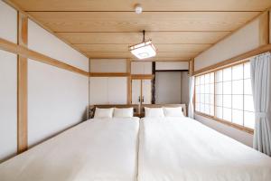 zwei Betten in einem Zimmer mit zwei Fenstern in der Unterkunft Landmark Annex in Furano