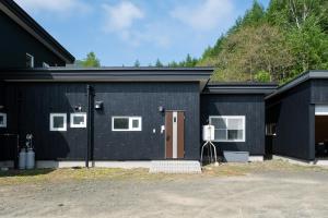 een zwart huis met een bruine deur erop bij Landmark Annex in Furano