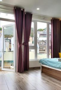 大叻的住宿－Ngô Gia Home，一间卧室配有床和两个带窗帘的窗户