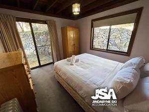 a bedroom with a large bed and two windows at Cedar Haven in Jindabyne